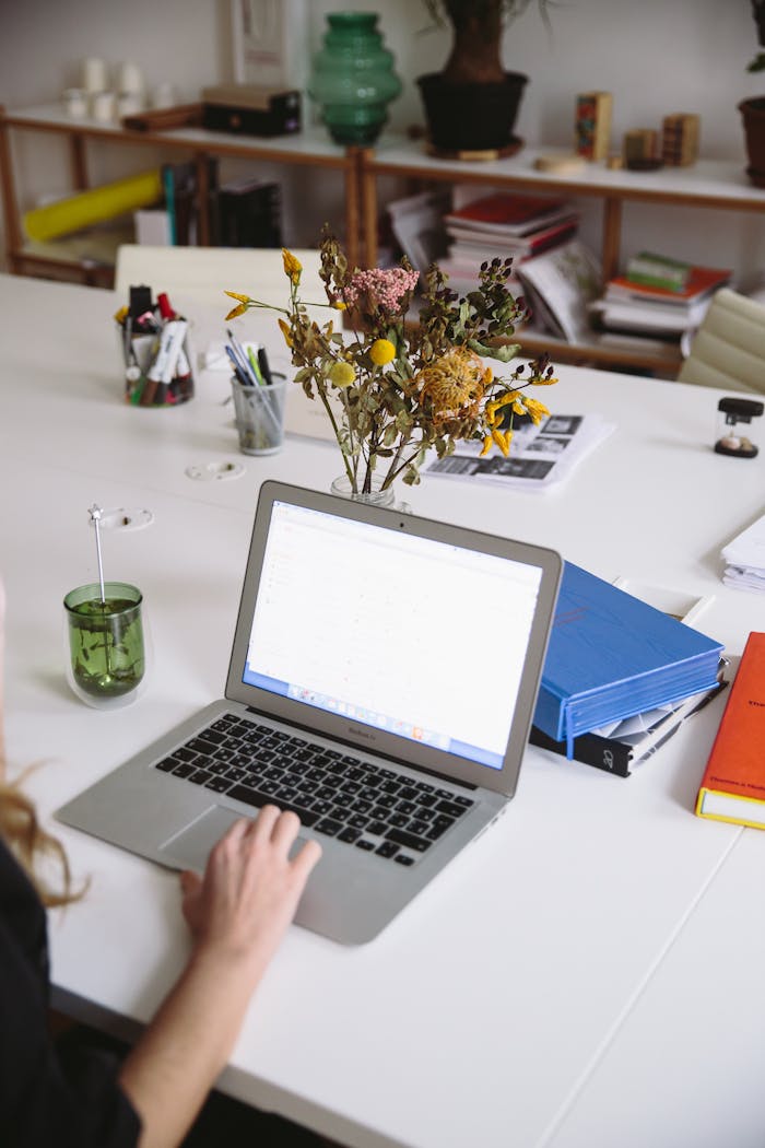 A modern workspace featuring a laptop, dry flowers, and office supplies, ideal for remote work.